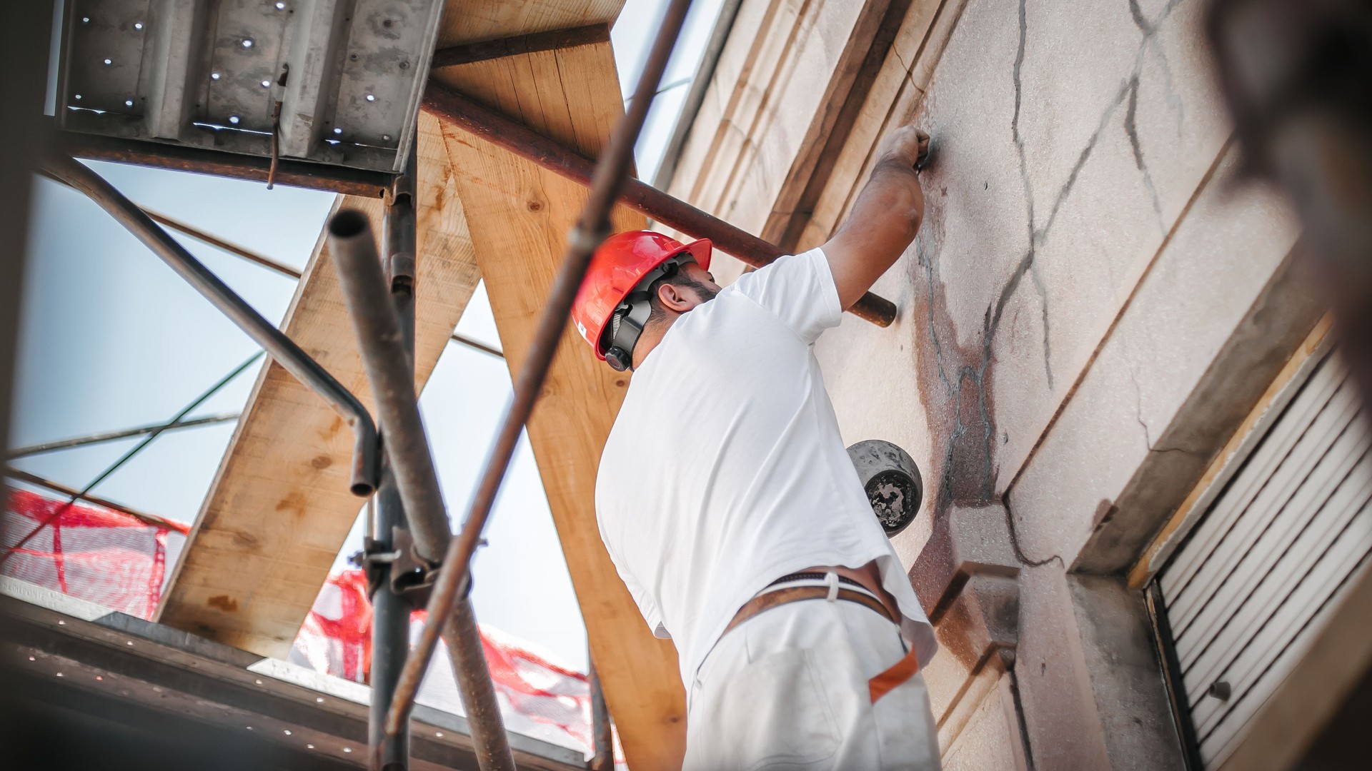 Man worker standing on scaffolding and restore old building facade